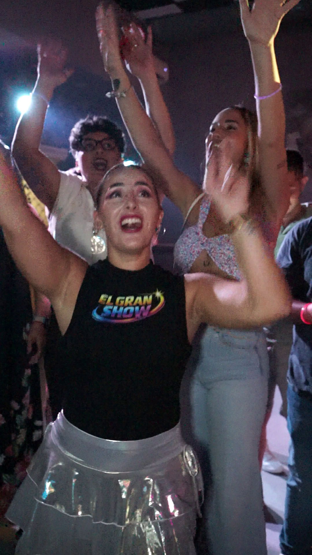 Una animadora con falda plateada y el público celebran con los brazos levantados