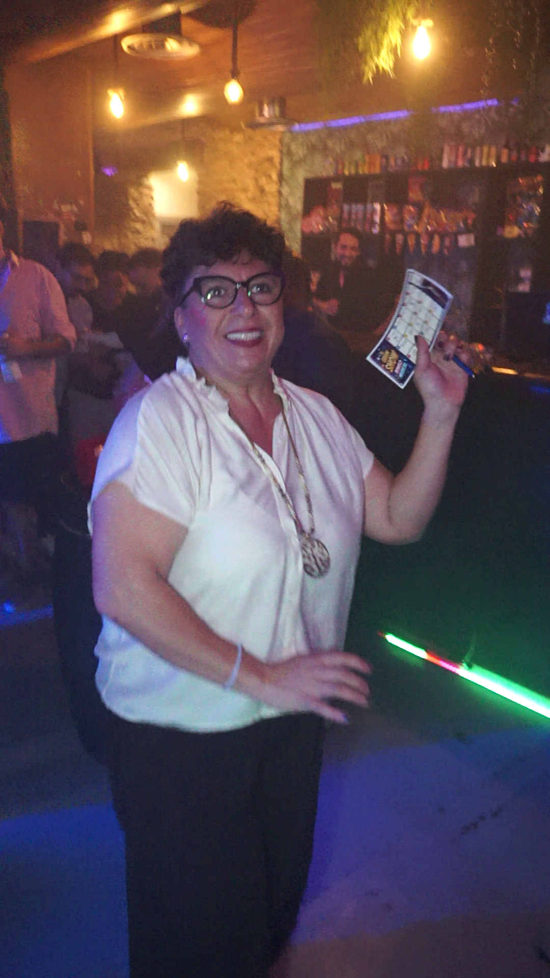 Una participante sonríe mostrando su cartón de bingo musical